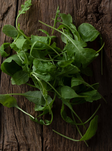 Fresh Eruca sativa leaves on wood