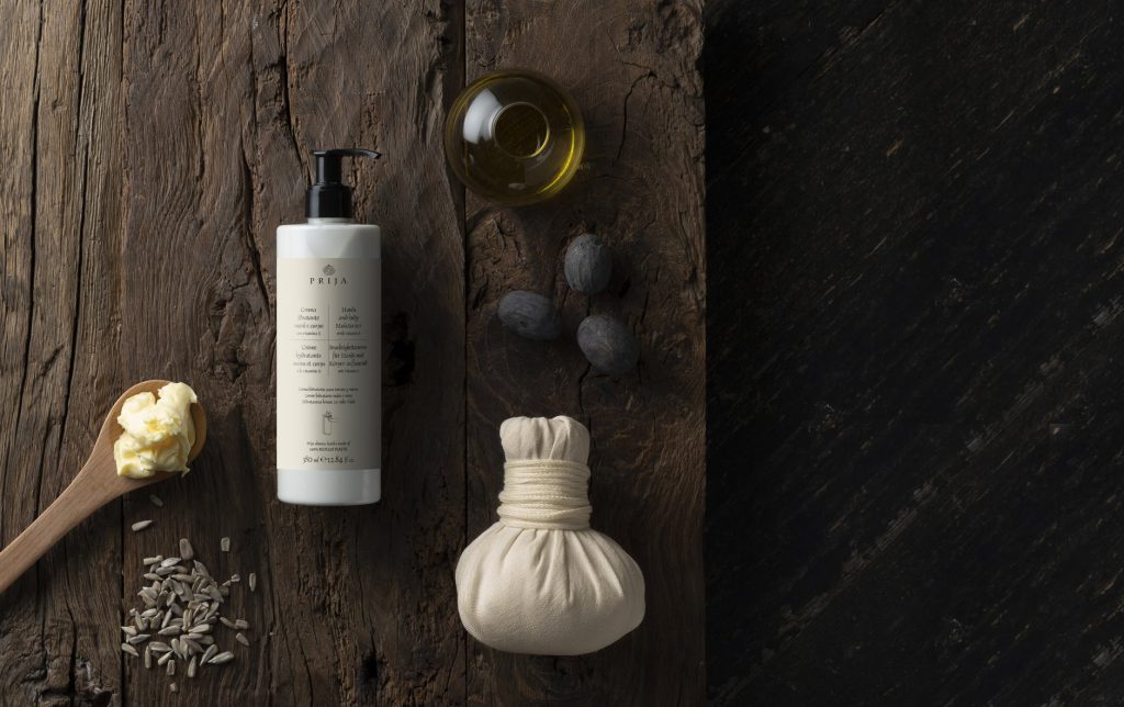 Prija hands and body moisturiser on dark wood with botanical ingredients
